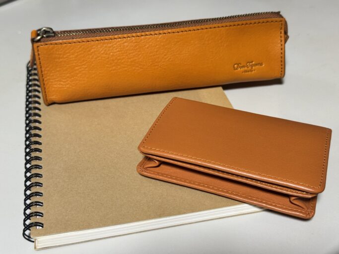 キャメル色のスリムなペンケースとカードケースをノートの上に並べて置いた様子
